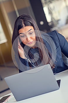 Young Latin Project Manager Putting On Headphones and Working on Laptop Computer in Busy Creative Office Environment.