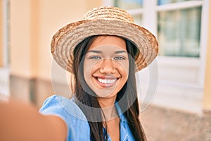 Young latin tourist girl on vacation smiling happy making selfie by the camera at the city
