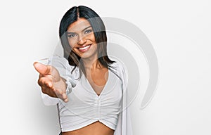 Young latin transsexual transgender woman wearing casual clothes smiling cheerful offering palm hand giving assistance and