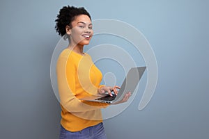 young latin woman with afro hair working remotely using laptop on studio background