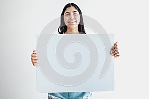 Young latin woman holding a blank empty card isolated on white background in Latin America