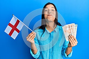 Giovane latino una donna possesso inghilterra bandiera un libbre banconote facce ridicolo 
