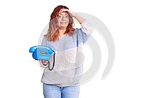 Young latin woman holding vintage telephone stressed and frustrated with hand on head, surprised and angry face