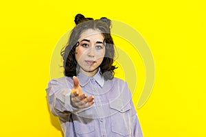 young latin woman isolated on yellow background offers for help, reaching hand of hand to the camera