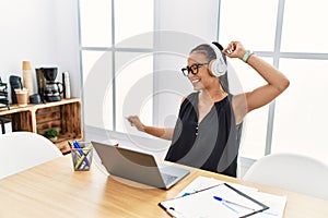 Young latin woman listening to music working at office