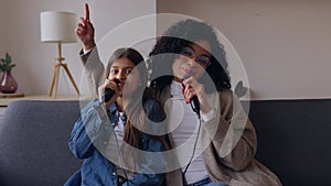 Young latin woman mother playing karaoke with her daughter at home