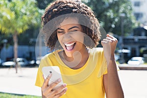 Young latin woman receiving good news by phone