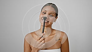 Young latin woman smiling confident holding make up brush over isolated white background