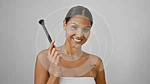 Young latin woman smiling confident holding make up brush over isolated white background