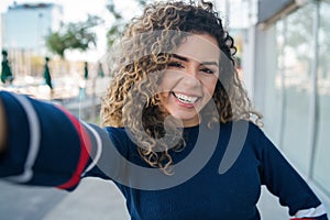 Young latin woman taking selfies outdoors.