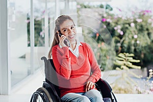 Young latin woman talking by phone in wheelchair at workplace in Mexico city
