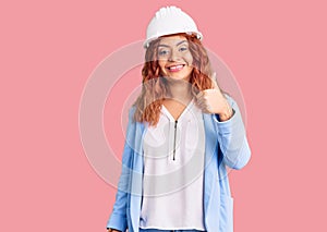 Young latin woman wearing architect hardhat doing happy thumbs up gesture with hand