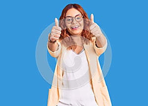 Young latin woman wearing business clothes approving doing positive gesture with hand, thumbs up smiling and happy for success