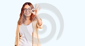 Young latin woman wearing business clothes smiling positive doing ok sign with hand and fingers