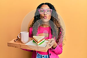 Young latin woman wearing business style having breakfast looking at the camera blowing a kiss being lovely and sexy
