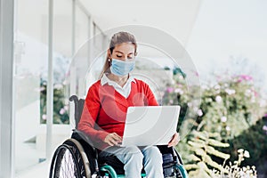 Young latin woman in wheelchair working with another woman colleague at workplace or office in Mexico city