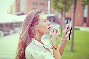 Young Latina woman applying lipstick before dating