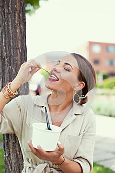 Young Latina woman enjoying eating fresh lettuce at park