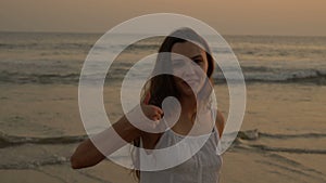 Young latino girl happily having fun and laughing at the ocean. Long dark hair. White dress.