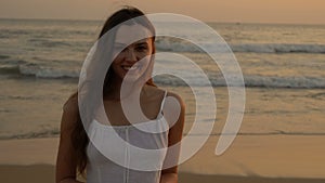 Young latino girl happily having fun and laughing at the ocean. Long dark hair. White dress.