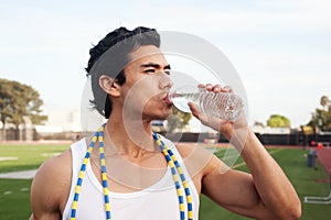 Young latino male athlete drinking water photo