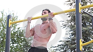 Young latino man in black pants doing exercises in a calisthenics