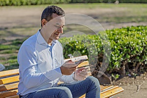 Young Latino man making a purchase with a credit card on his mobile phone in a public park