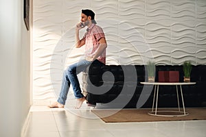 Young Latino Man Talking On Cell Phone At Home