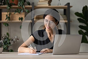 Young Latino woman handwrite working online on computer