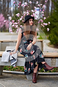 Young latino woman sitting on bench in the park