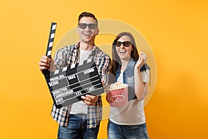 Young laughing couple woman man in 3d glasses watching movie film on date holding classic black film making clapperboard