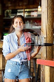 Young laughing female server with tray of drinks