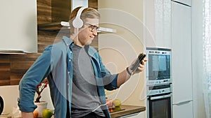 Young laughing man watching streaming movie on digital tablet eating cereals with headphones