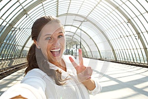 Young laughing woman taking selfie with peace sign