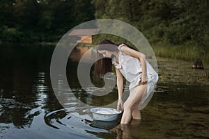 Young laundress stands in the river