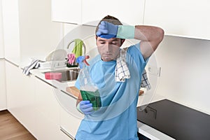 Young lazy house cleaner man washing and cleaning the kitchen with detergent spray bottle