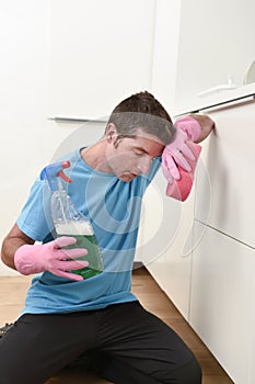 Young lazy house cleaner man washing and cleaning the kitchen with detergent spray bottle