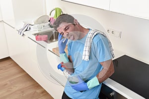 Young lazy house cleaner man washing and cleaning the kitchen with detergent spray bottle