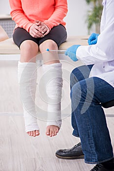 Young leg injured woman visiting old doctor traumatologist