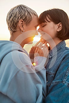 Young lesbian couple having romantic moment, Two girls going to kiss while watching the sunrise together