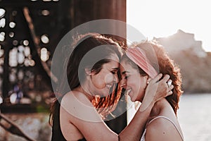 Young lesbian couple hugging at sunset outdoors. Lifestyle and pride concept. love is love