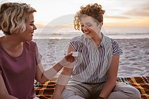 Young lesbian couple sitting on a beach blanket at dusk