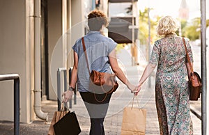 Young lesbian couple walking in the city carrying shopping bags