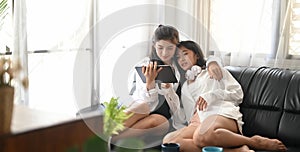 Young Lesbian couple are watching a movie on a computer tablet while sitting together on the sofa