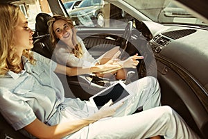 Young lesbian`s couple preparing for vacation trip on the car in sunny day