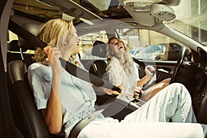 Young lesbian`s couple preparing for vacation trip on the car in sunny day