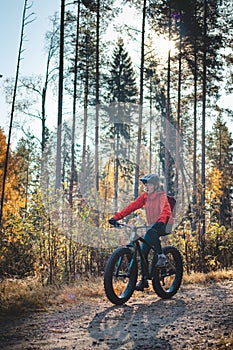 Young likeable lady with a lovely realistic smile while recreationally sporting. Cyclist riding fat bike in Finnish wild nature.