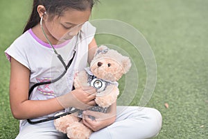 Young little asian girl playing pretend to be a doctor. young girl eaxamine her teddy bear with stethoscope