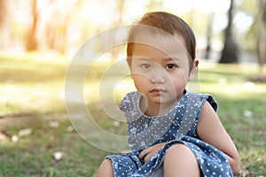 Young Little Asian kid sitting on grass outdoor park depressed and worry for distress, crying angry and afraid. Sad expression