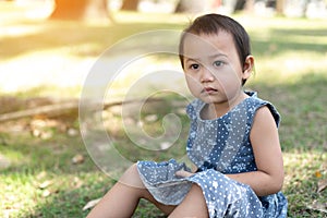 Young Little Asian kid sitting on grass outdoor park depressed and worry for distress, crying angry and afraid. Sad expression